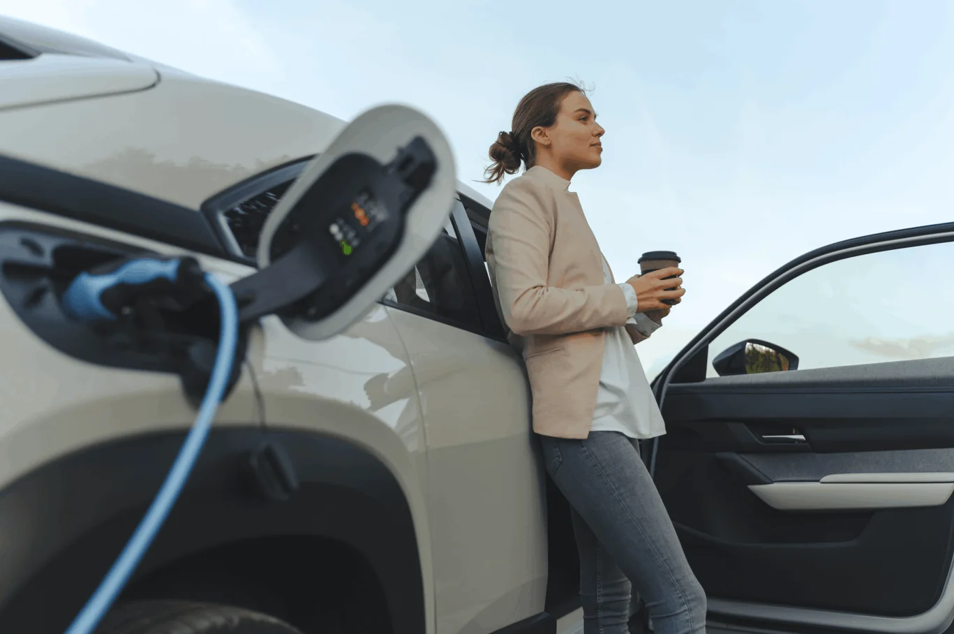 Mujer cargando su auto eléctrico, electromovilidad Sinergic